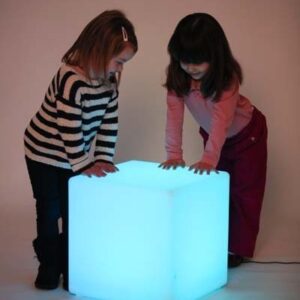 Two children playing with a sensory mood cube lit in blue