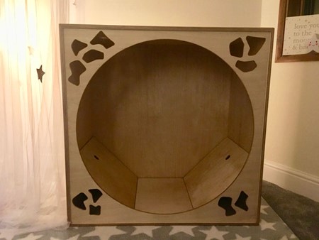 Wooden Sensory Den with circular entrance and cut out abstract shapes in each corner of the front
