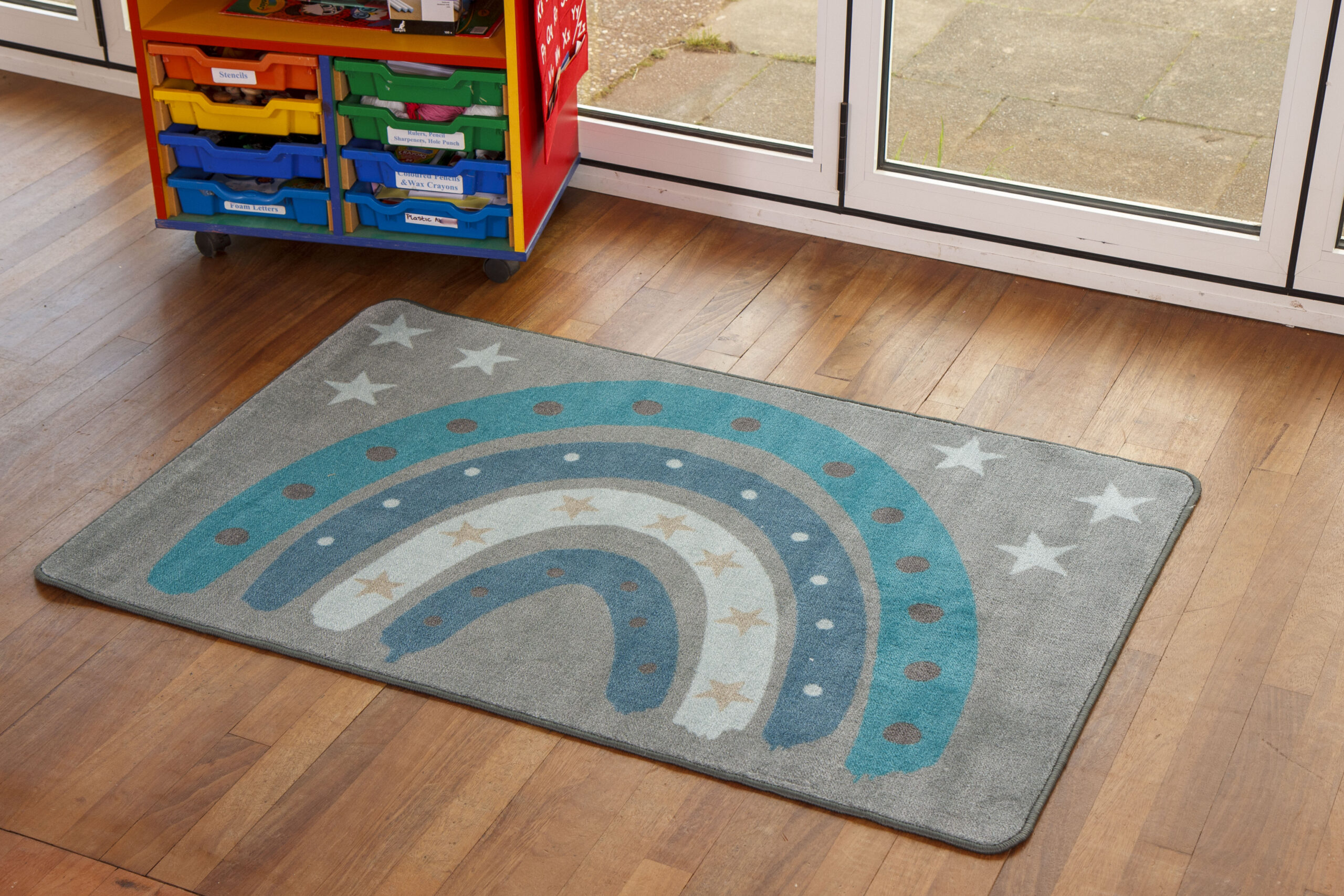 Nursery rug featuring grey background with rainbow in shades of blue
