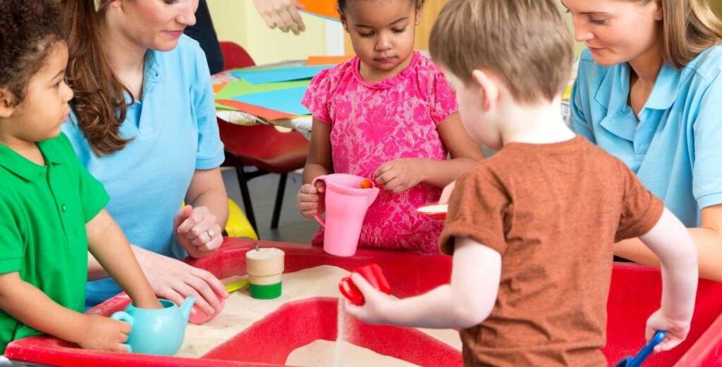 teachers and children in nursery - sand and water play in schools