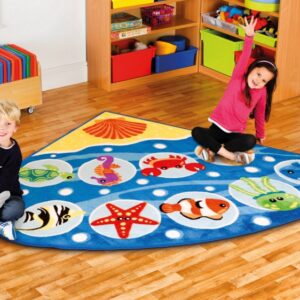 Corner classroom carpet featuring images of sea creatures. Two children sat on carpet raising hands to answer questions