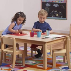 Two children sitting at a rectangular wooden classroom table in a classroom setting