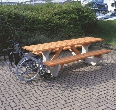 Large picnic bench with concrete base and wooden top. The wooden top overhangs to allow wheelchair access.