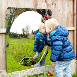 Little boy looking in a giant acrylic mirror panel with dome in centre creating distortion