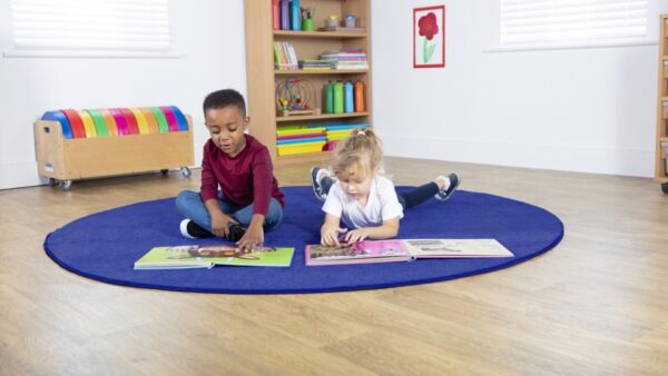 Two children reading on a Luxury Circular Classroom Carpet in blue