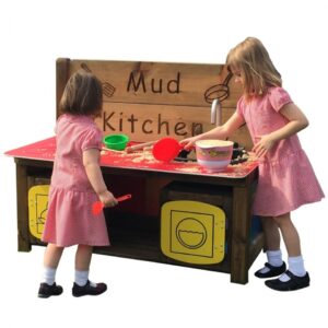 Two children playing in a mud kitchen with bright red worktop, sink, hob, washing machine and oven