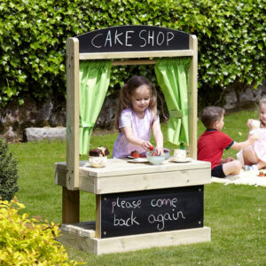 Wooden play shop theatre with green curtains and chalkboard above and below. Child using it as a pretend cake shop