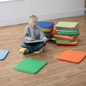 Boy sat in a classroom surrounded by Rainbow Square Cushions