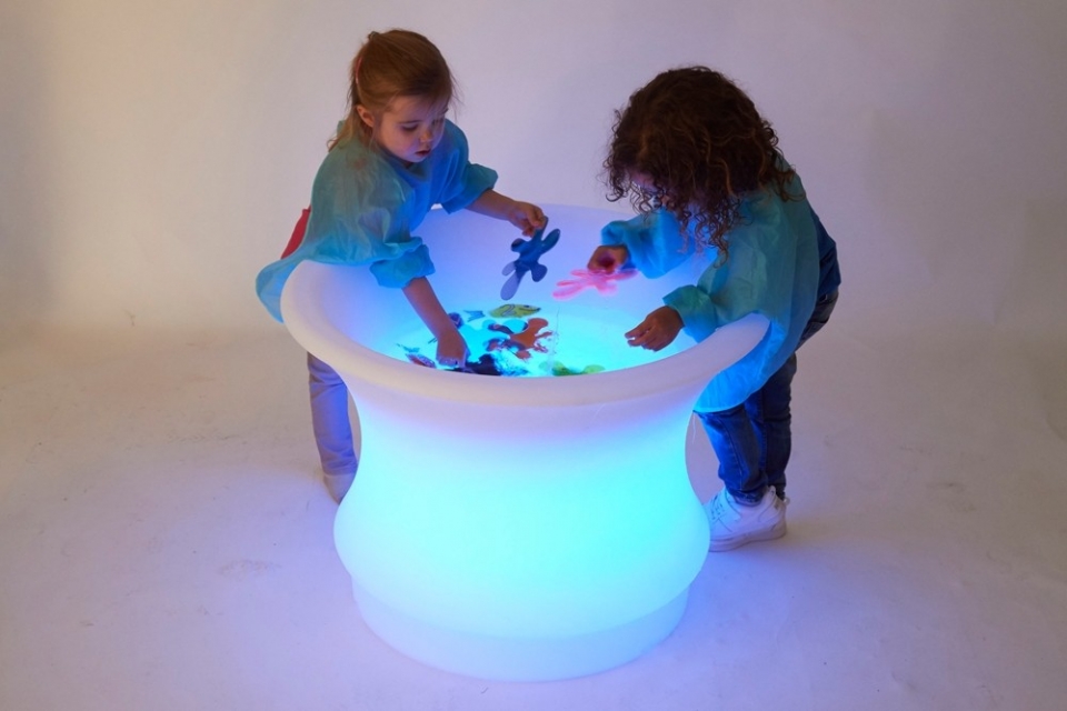 Circular sensory mood water table lit up with two children playing in the water
