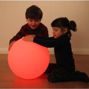 Two children playing with sensory mood ball lit in red