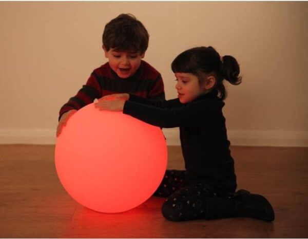 Two children playing with sensory mood ball lit in red