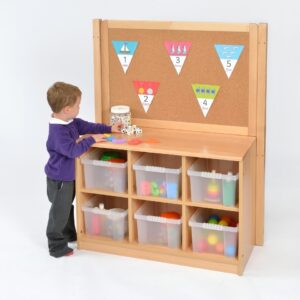 Child standing in front of a Room Scenes Storage Unit with Cork Divider and six clear storage trays
