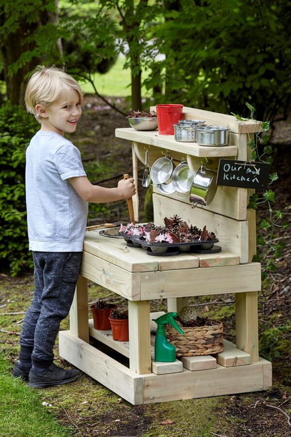 Boy playing at small wooden mud kitchen