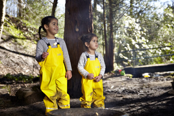Children wearing yellow Forest Ranger dungarees playing outside