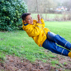 Child on rope swing wearing Spotty Otter Forest Leader jacket and dungarees