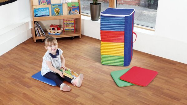 Child sat in front of pack of square classroom cushions with holdall